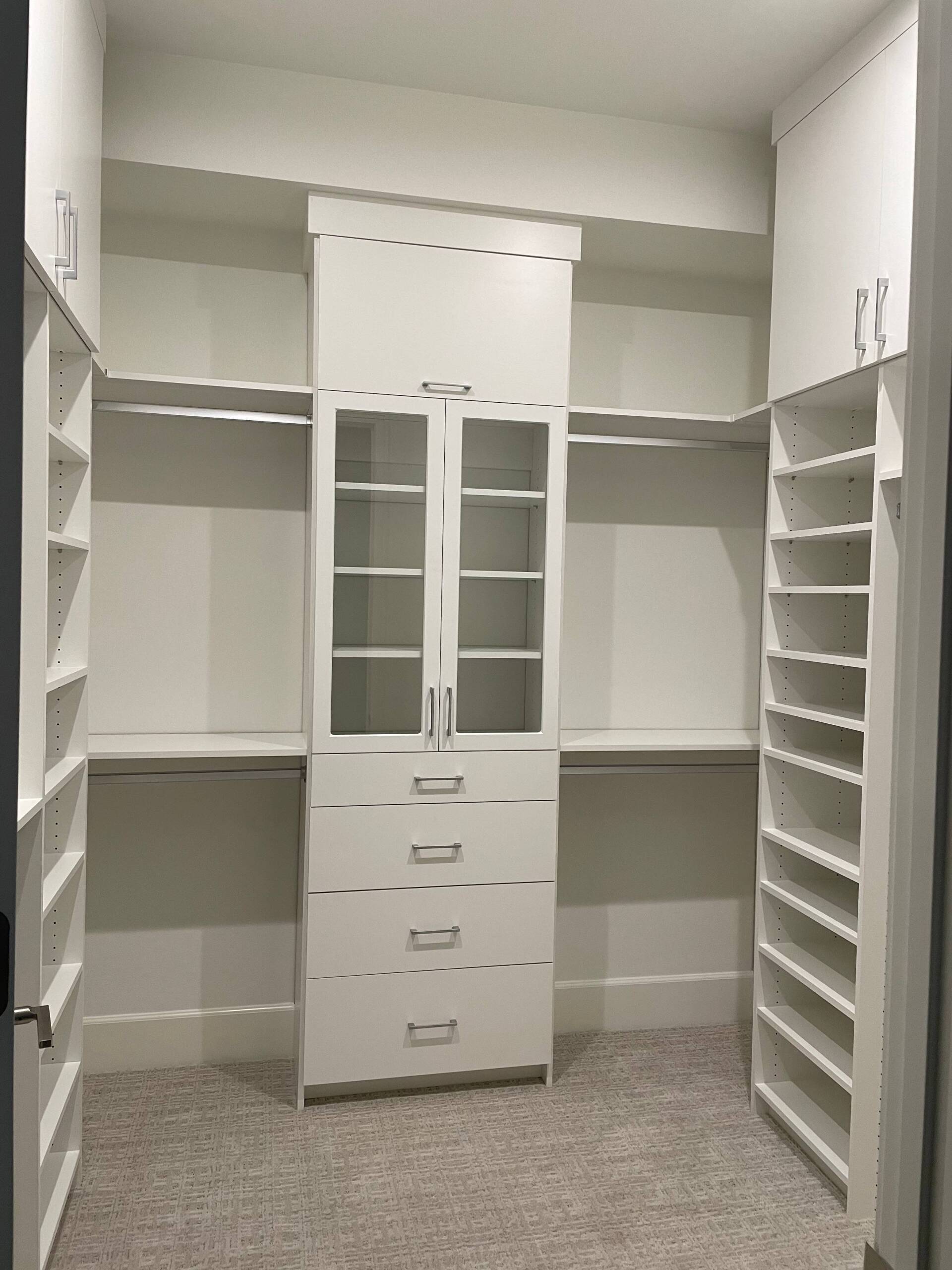 a custom walk in closet with lots of shelves and drawers .