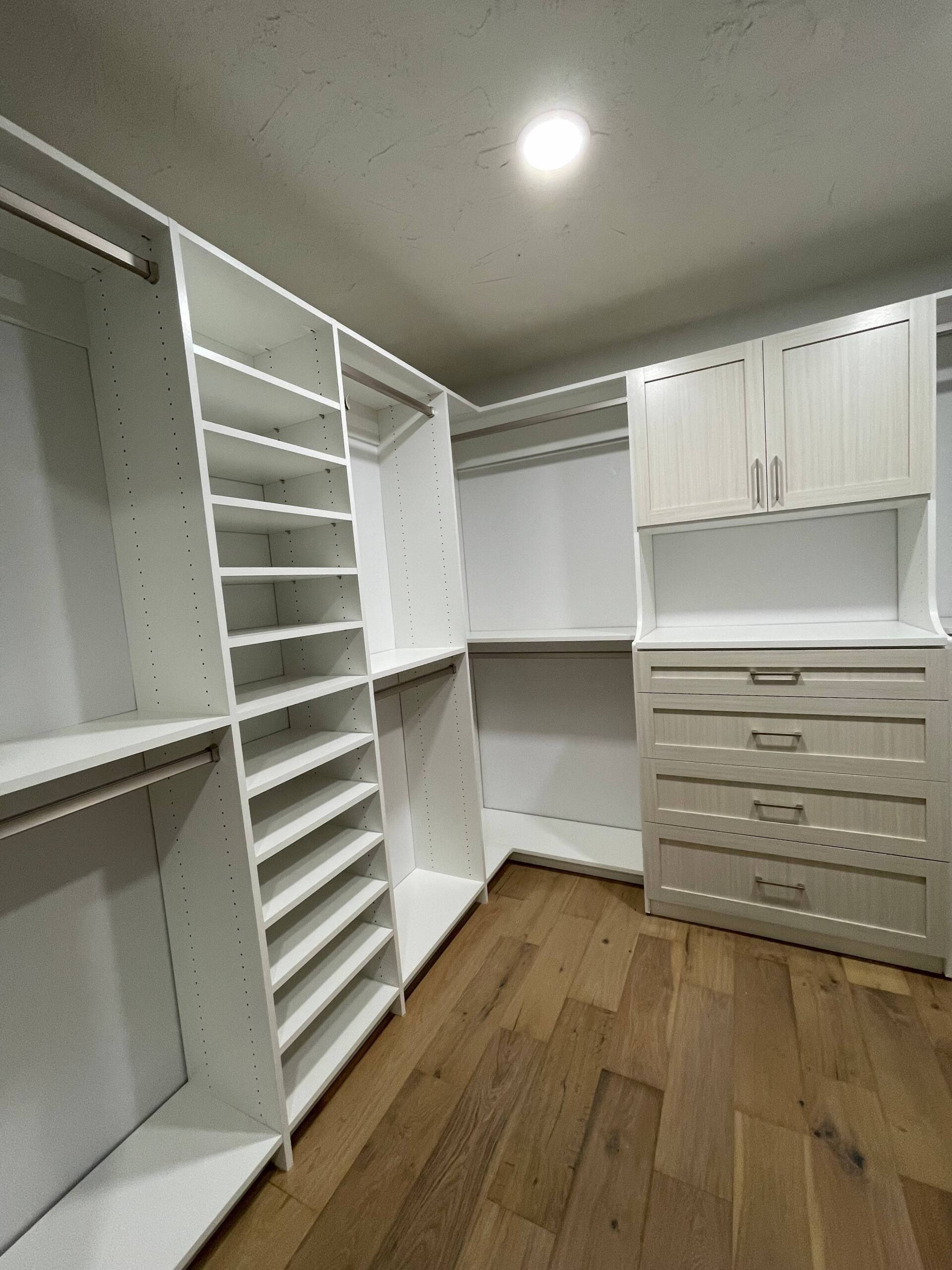 a walk in closet system with lots of shelves and drawers