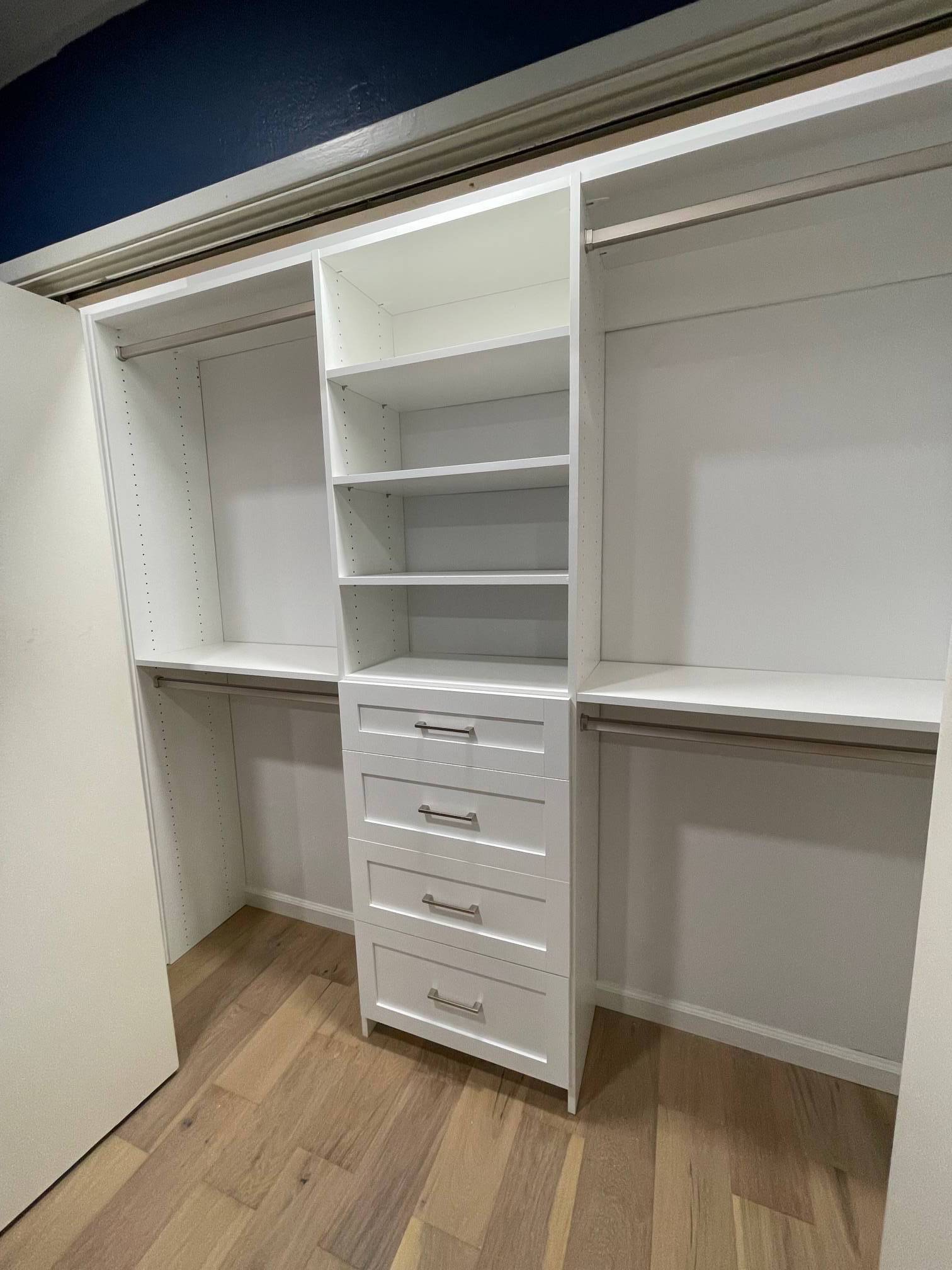 a walk in closet with lots of shelves and drawers .