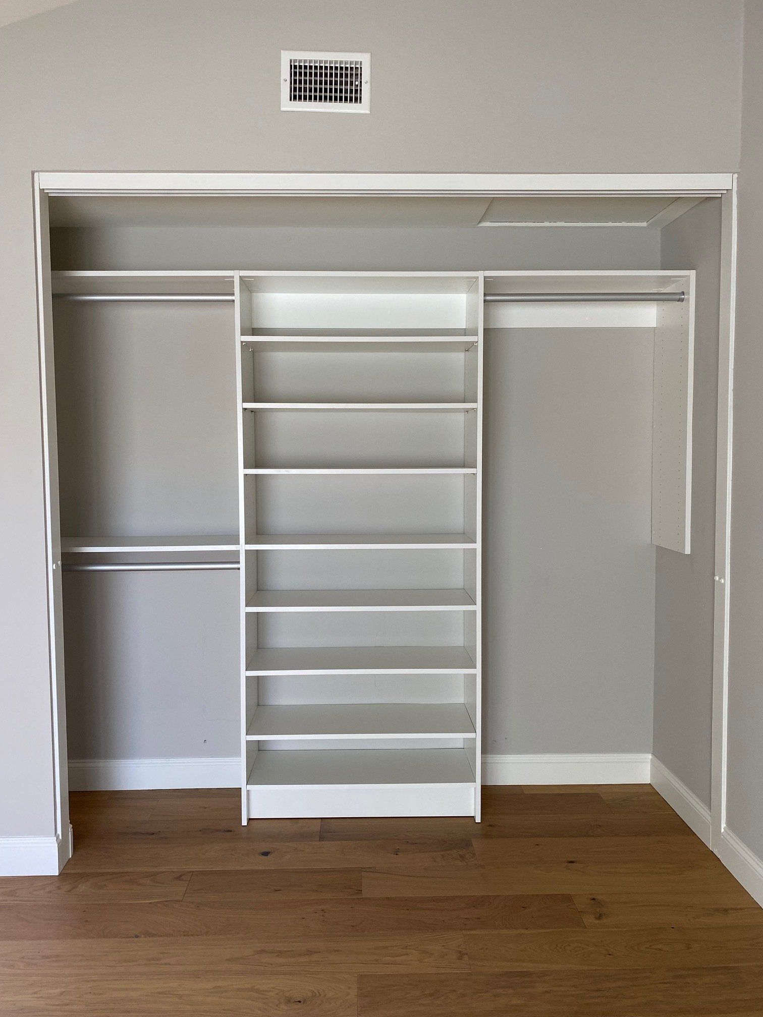 a reach in closet with a lot of shelves and a wooden floor .