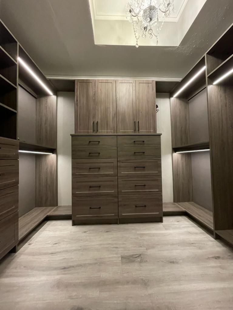 a walk in closet with lots of drawers and cabinets and a chandelier .