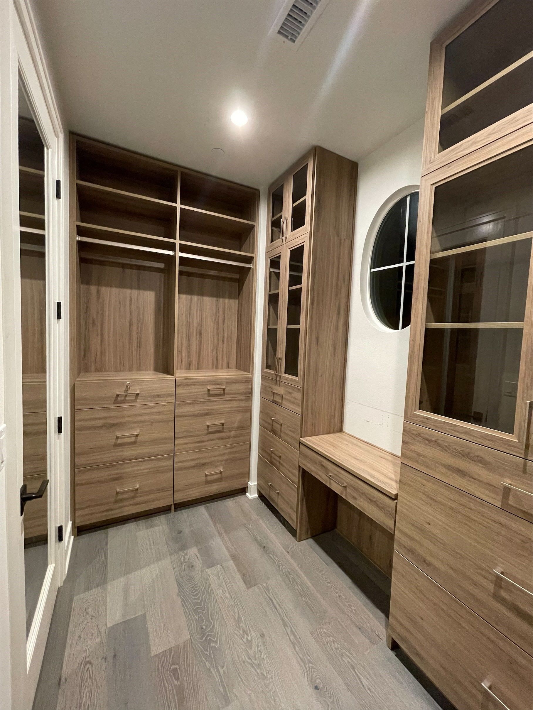 a walk in closet with lots of tahoe finish cabinets and drawers .