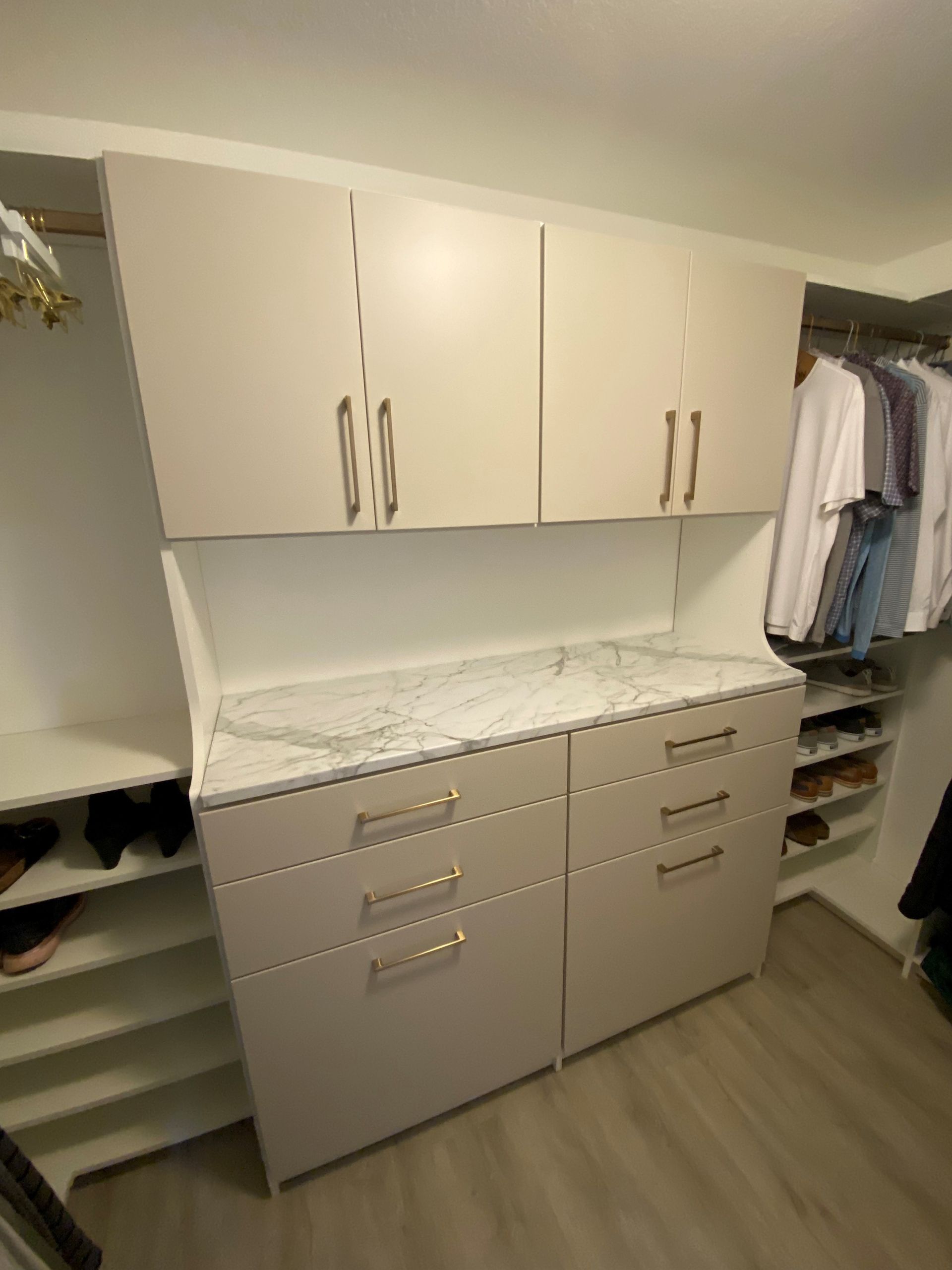 a walk in closet with white cabinets , drawers , and shelves .