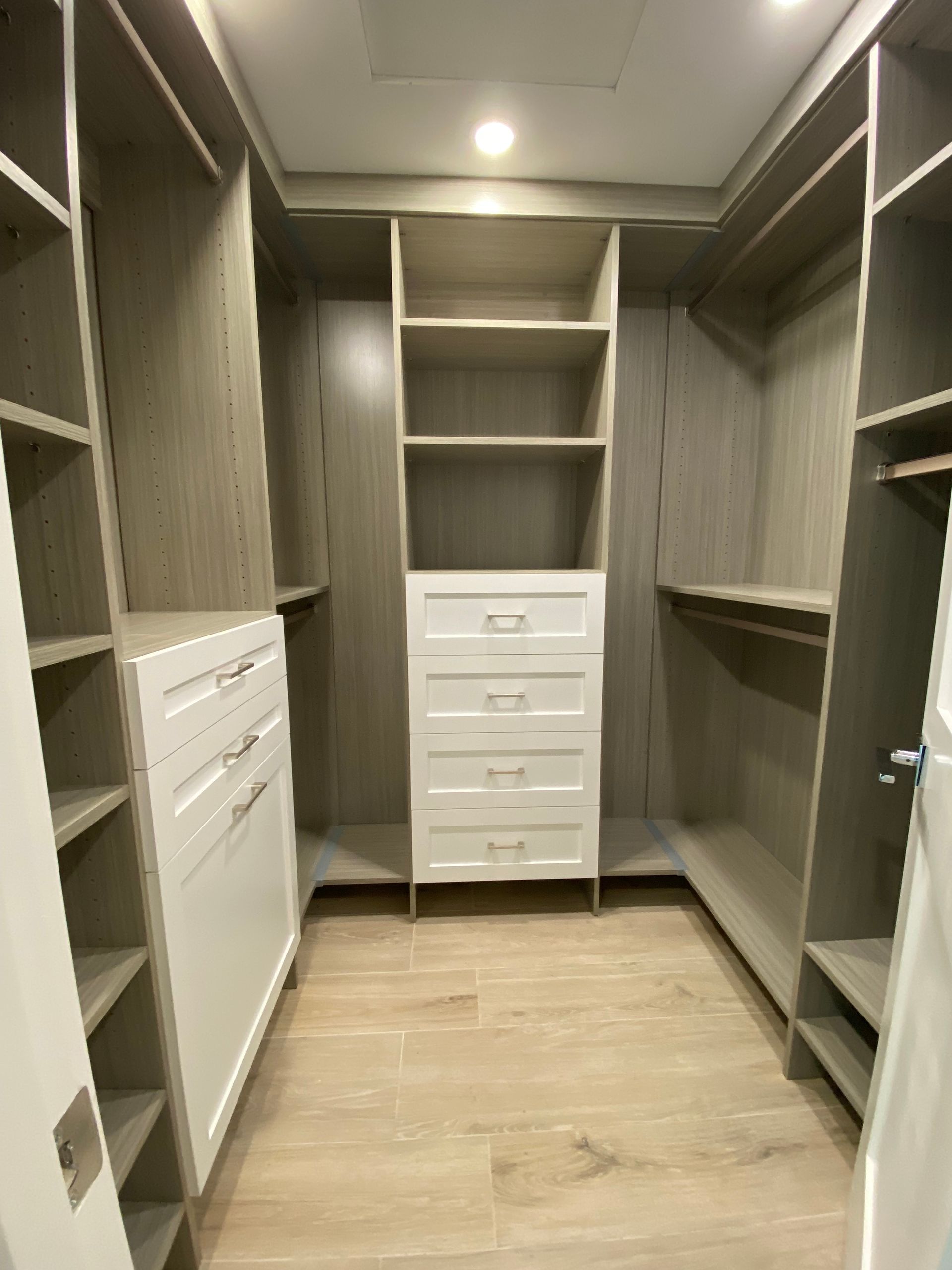 a walk in closet with lots of shelves and drawers .