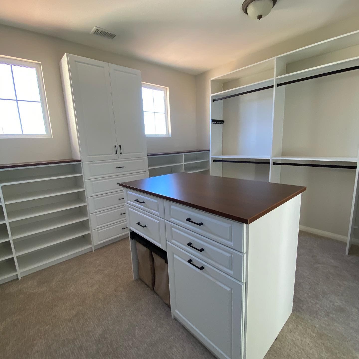 a walk in closet with a large island in the middle .