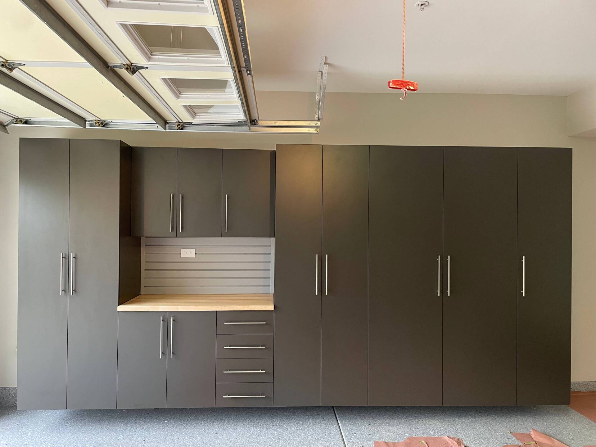 a garage with a lot of cabinets and drawers and a garage door open .