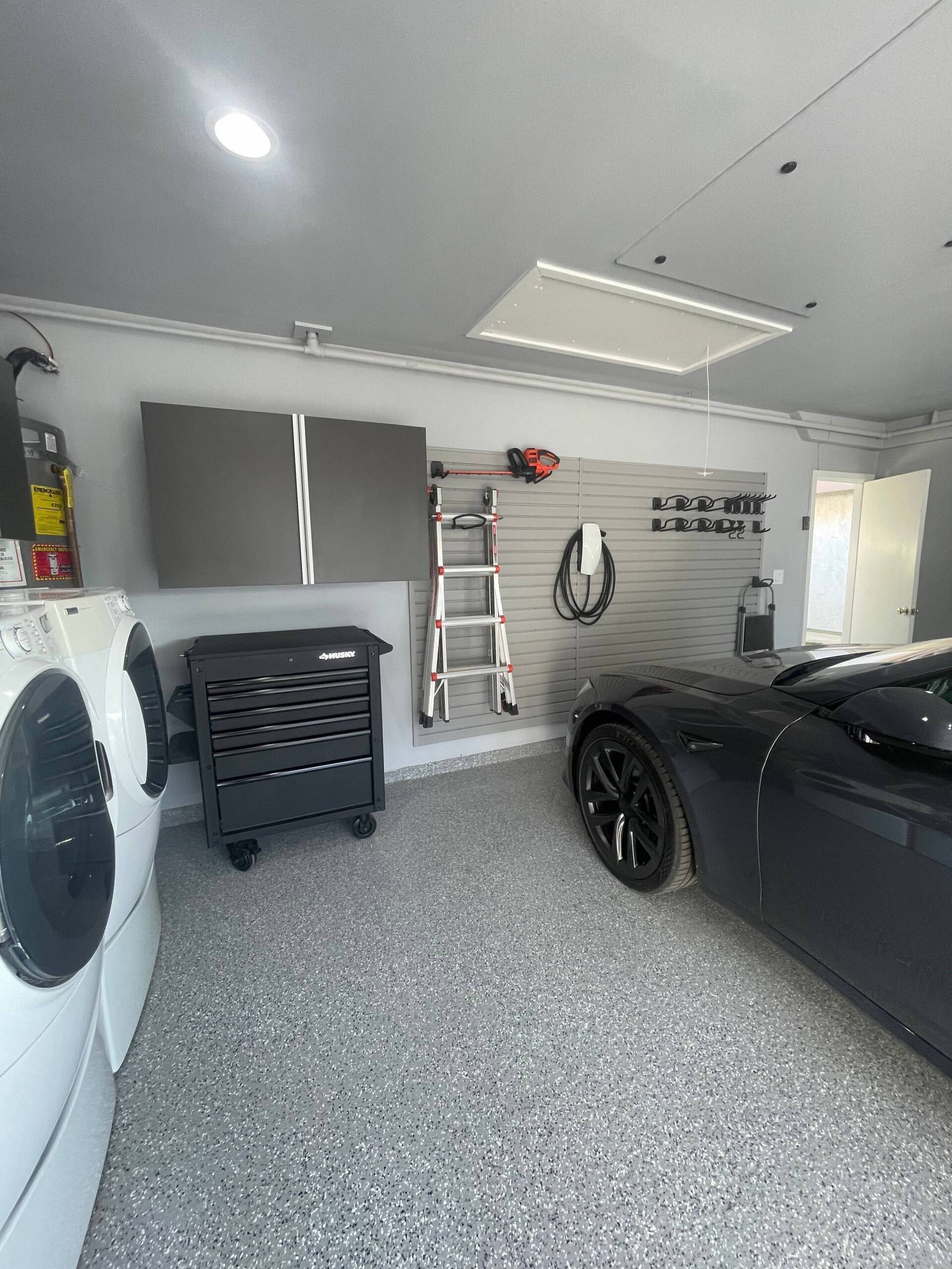 a car is parked in a garage next to a washer and dryer and custom garage cabinets