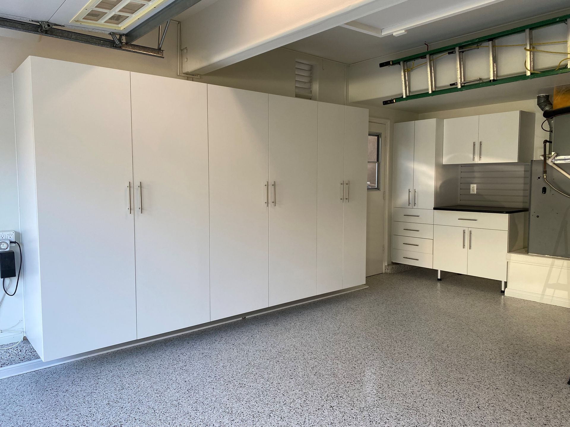 a garage with white cabinets and a ladder on the ceiling .