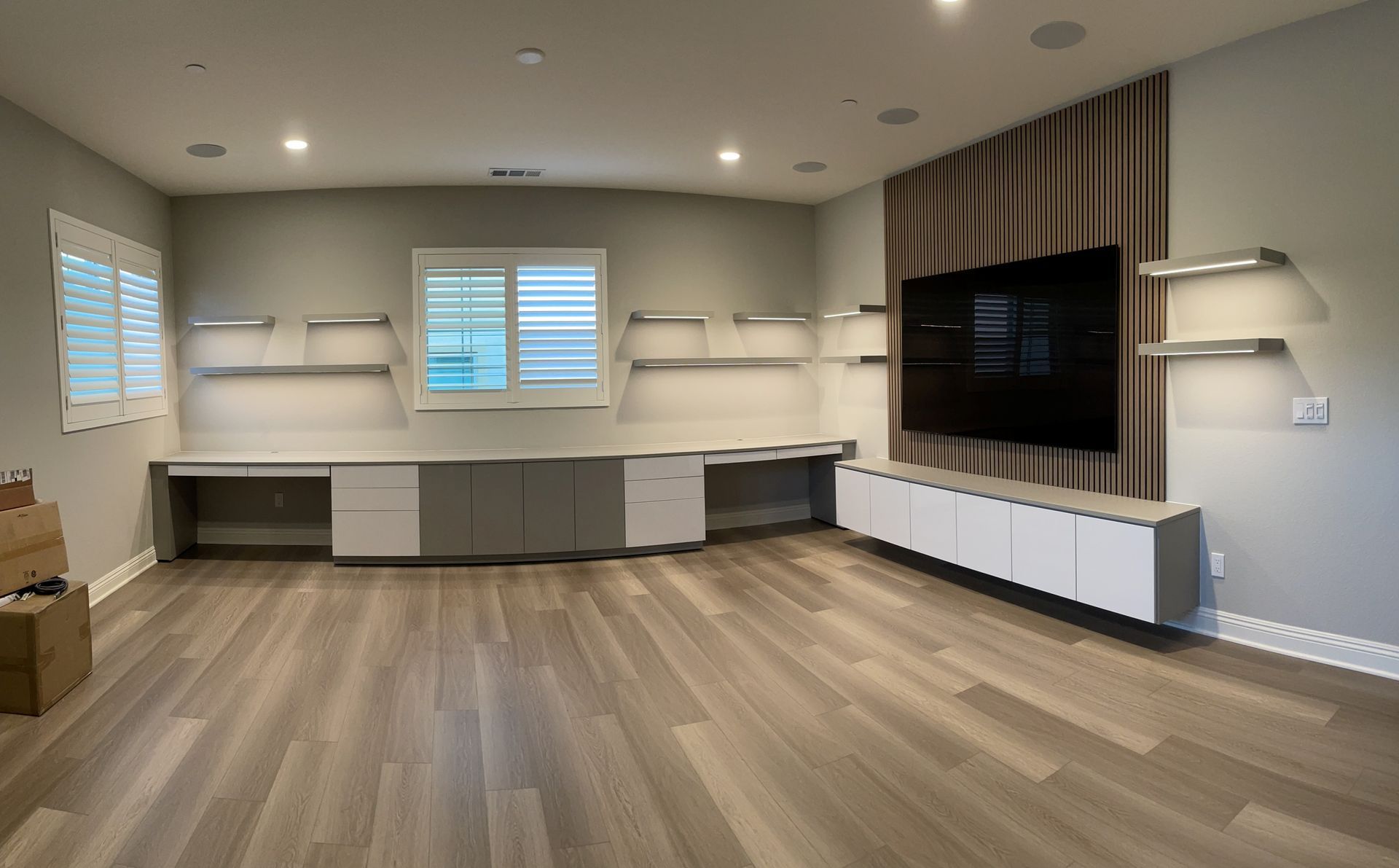 a living room with hardwood floors and a flat screen tv on the wall and custom cabinetry