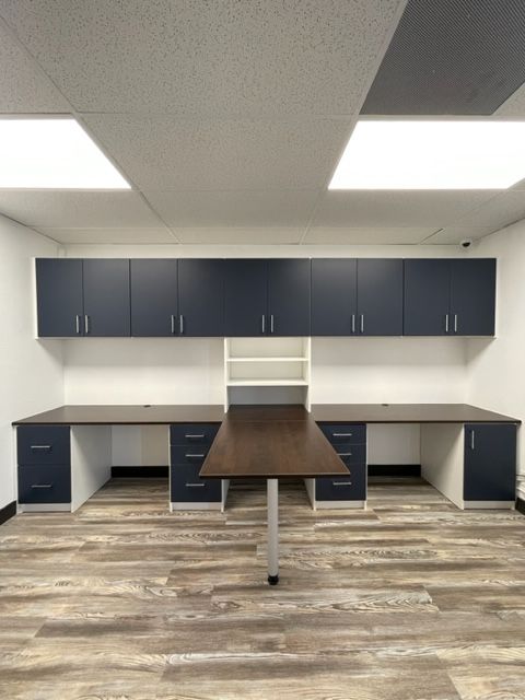 a room with two desks and cabinets on the wall .