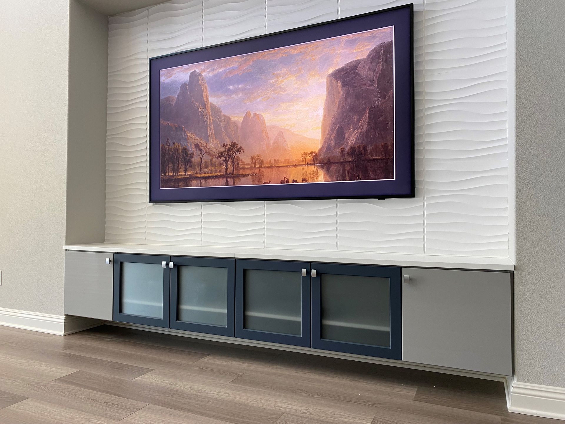 a flat screen tv is hanging on a wall above an entertainment center .