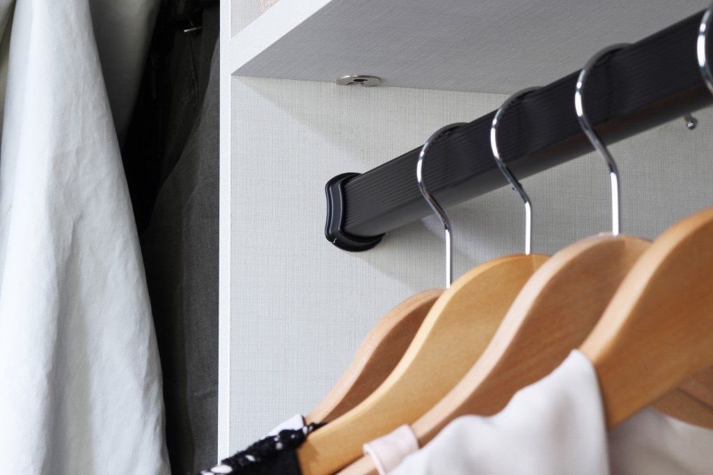 a close up of a closet with clothes hanging on a rod .