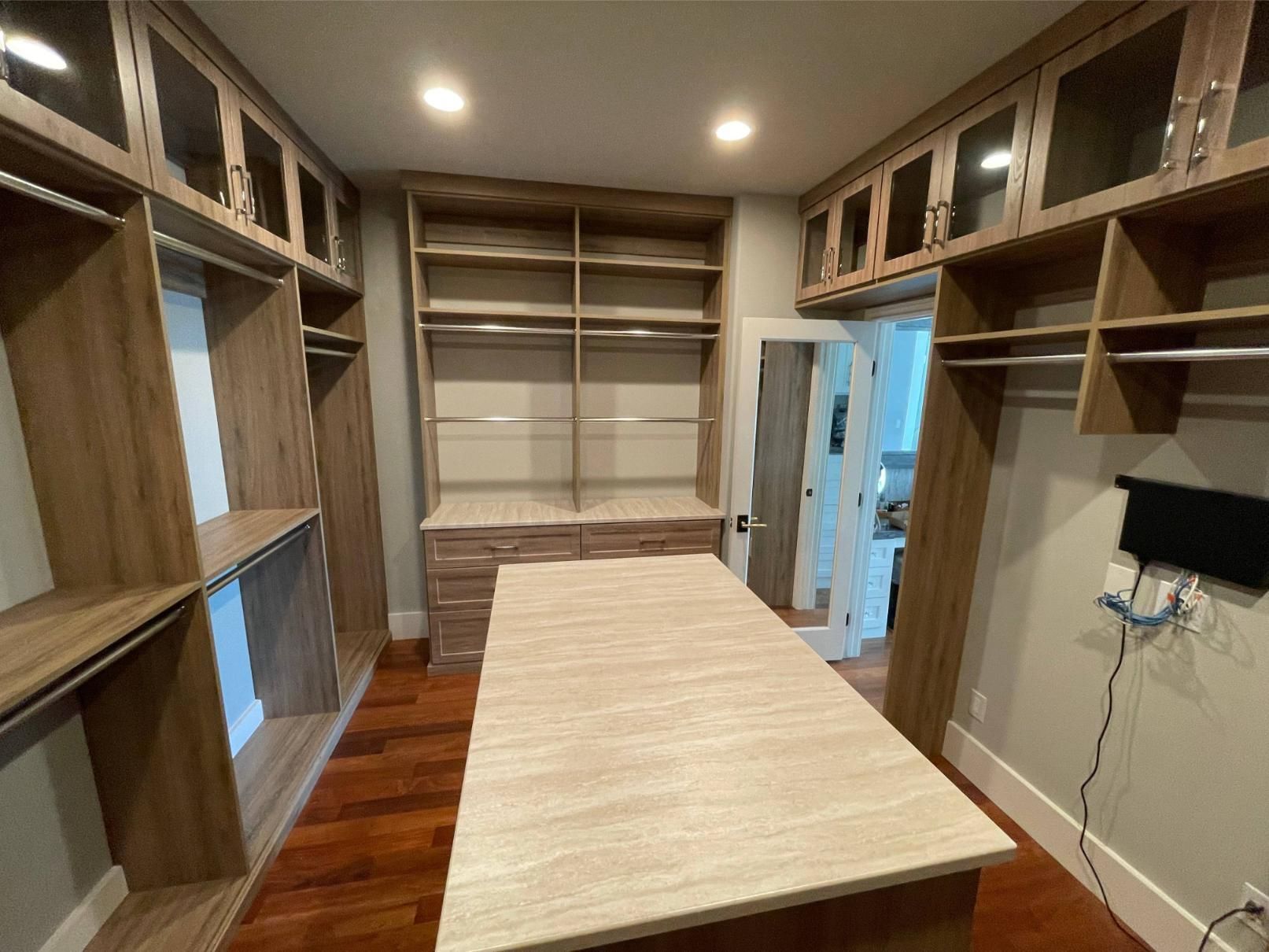A walk in closet with a large island, shelving, and drawers.