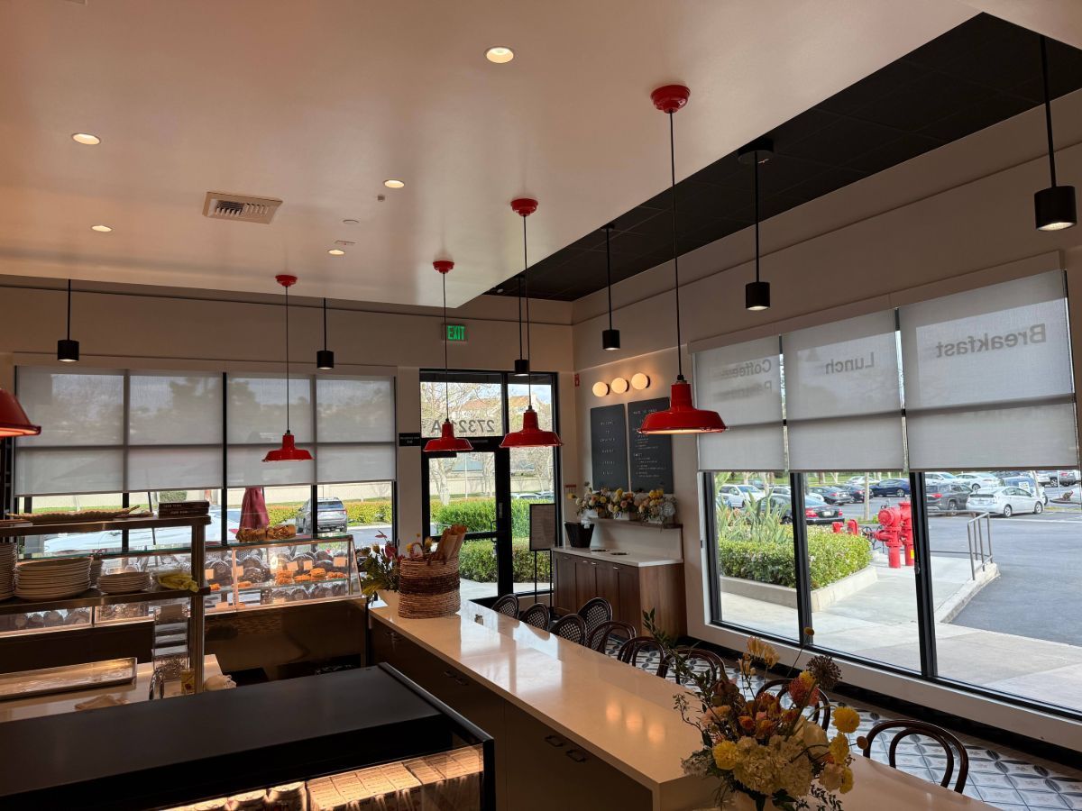 The inside of a bakery with a long counter and lots of windows.