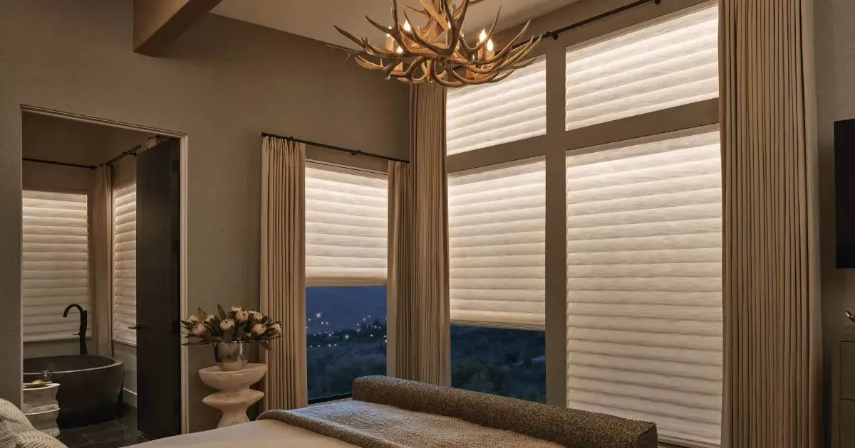 A bedroom with a large bed , a chandelier , and lots of windows.