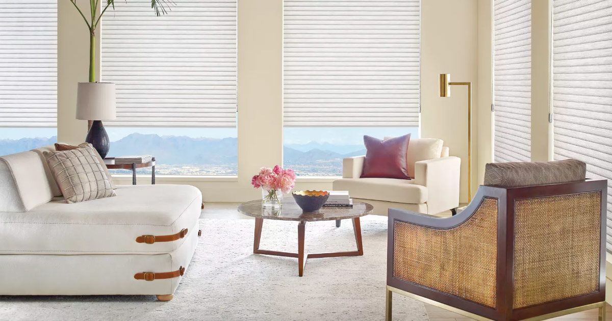 A living room with a white couch , chair , table and window.