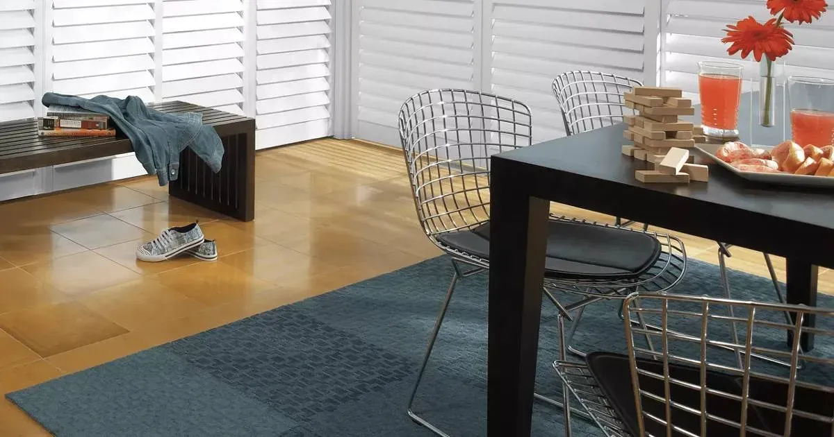 a spacious room with blinds on a large window and a wooden floor.