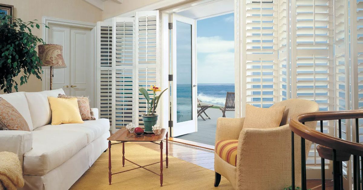 A living room with a couch and chairs and a view of the ocean.