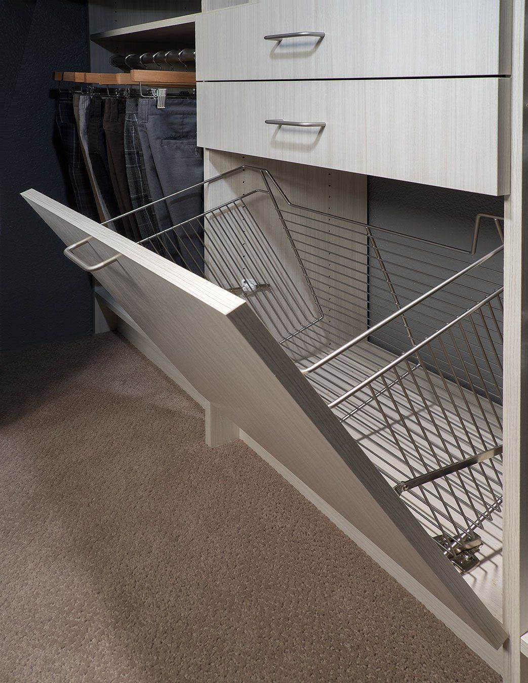 a closet with drawers and a laundry hamper open