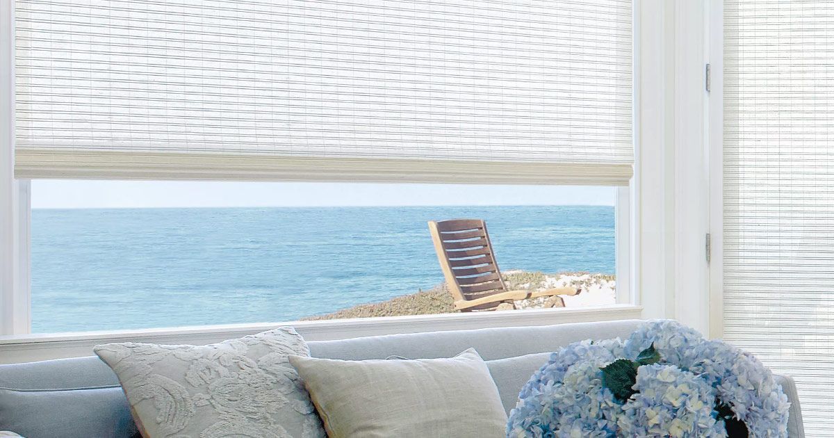 A living room with a couch and a window looking out to the ocean.