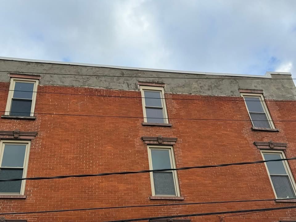 Brick building with rectangular windows and overcast sky.