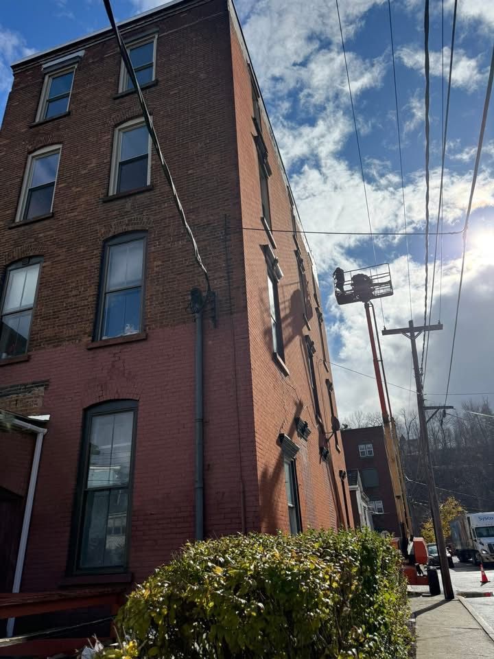 Tall brick building with windows, power lines overhead, sunny day.
