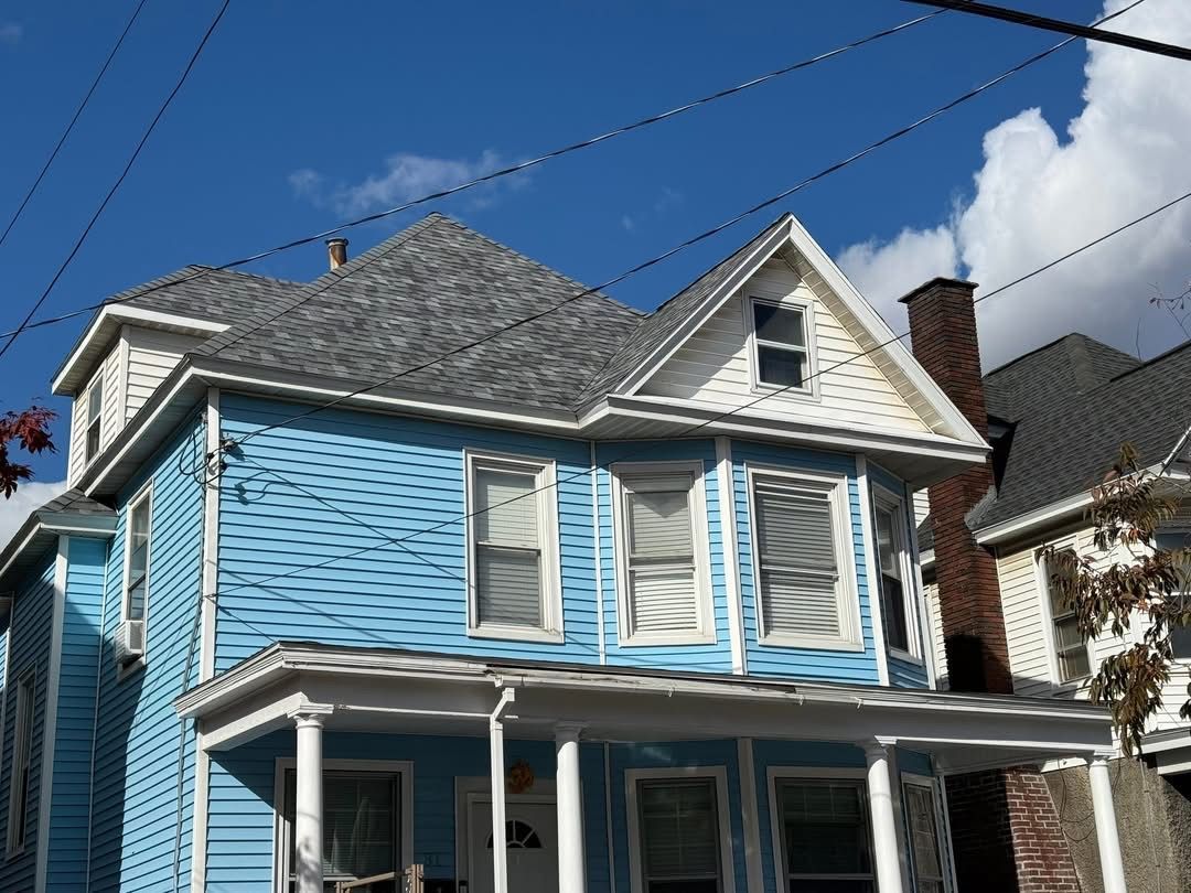 Blue two-story house with white trim under a blue sky.