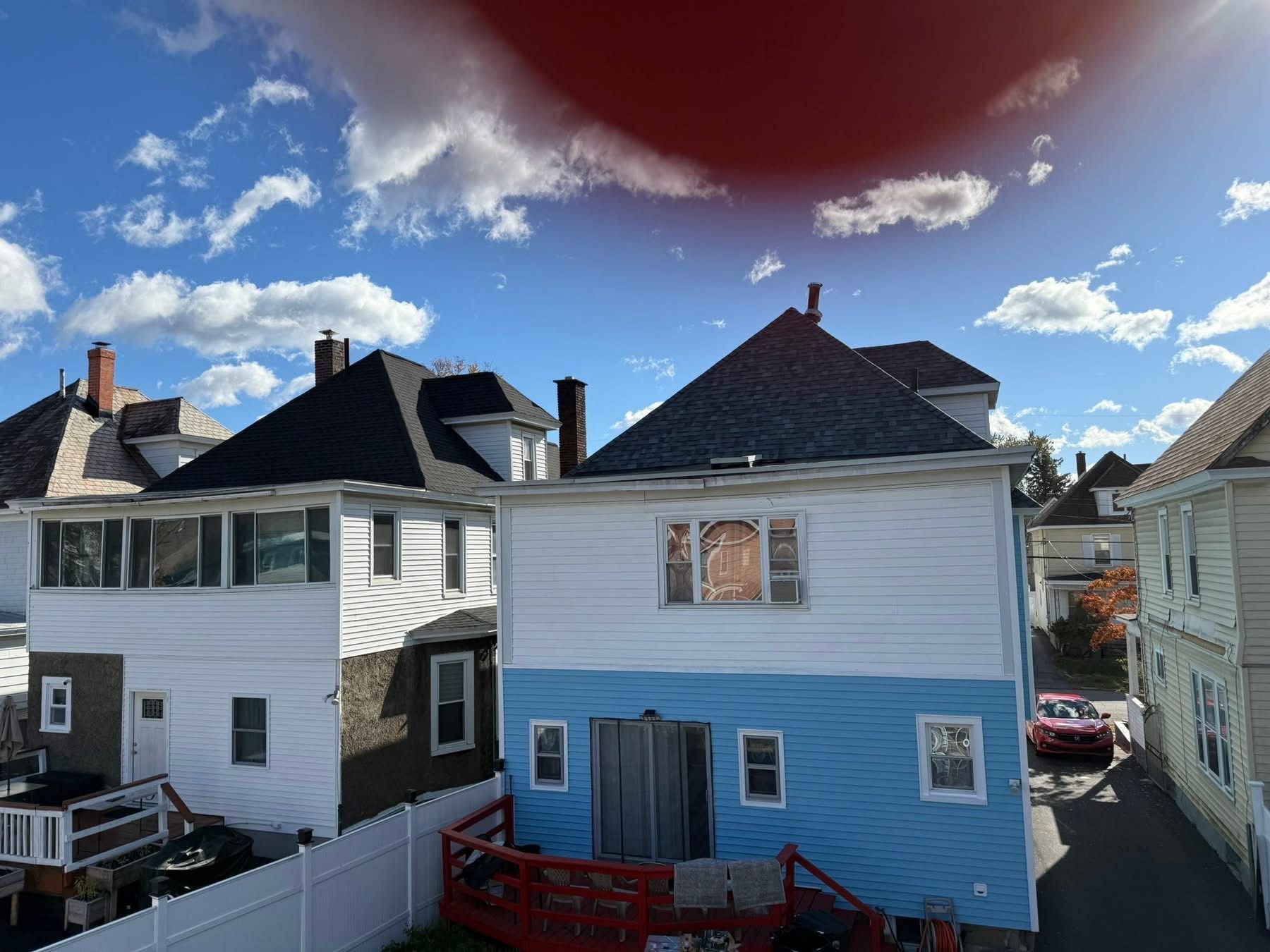 Two-story houses with blue and white siding under a sunny sky with clouds.
