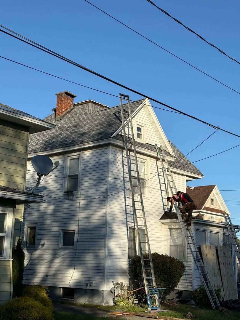 Two ladders against a white house, roof work in progress, clear blue sky.