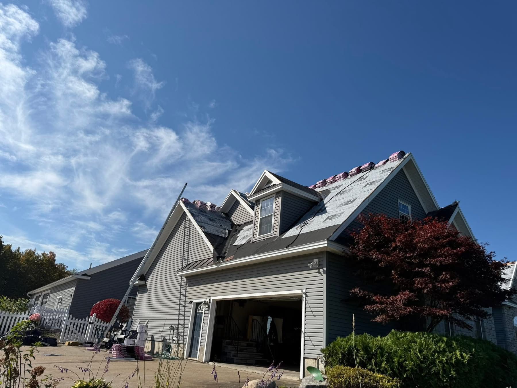 House with new roofing under a blue sky with some clouds.