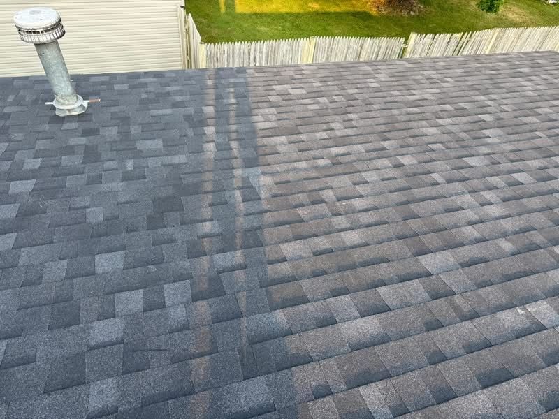 Dark gray asphalt shingles on a roof, transitioning to a lighter color.  A vent pipe is visible.