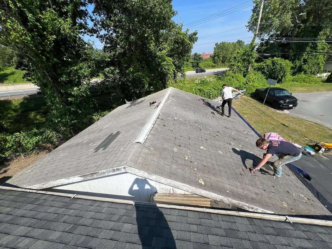 People on a roof repairing shingles on a sunny day.