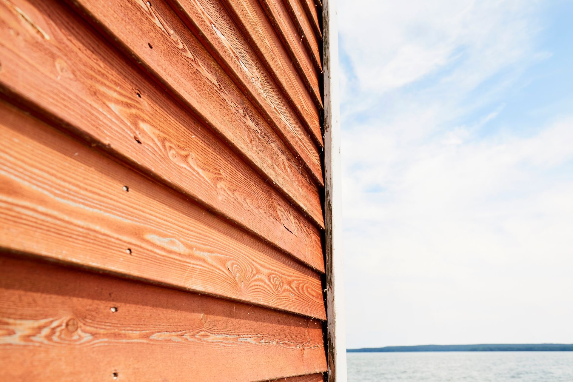 A close up of a wooden wall with a view of the ocean.