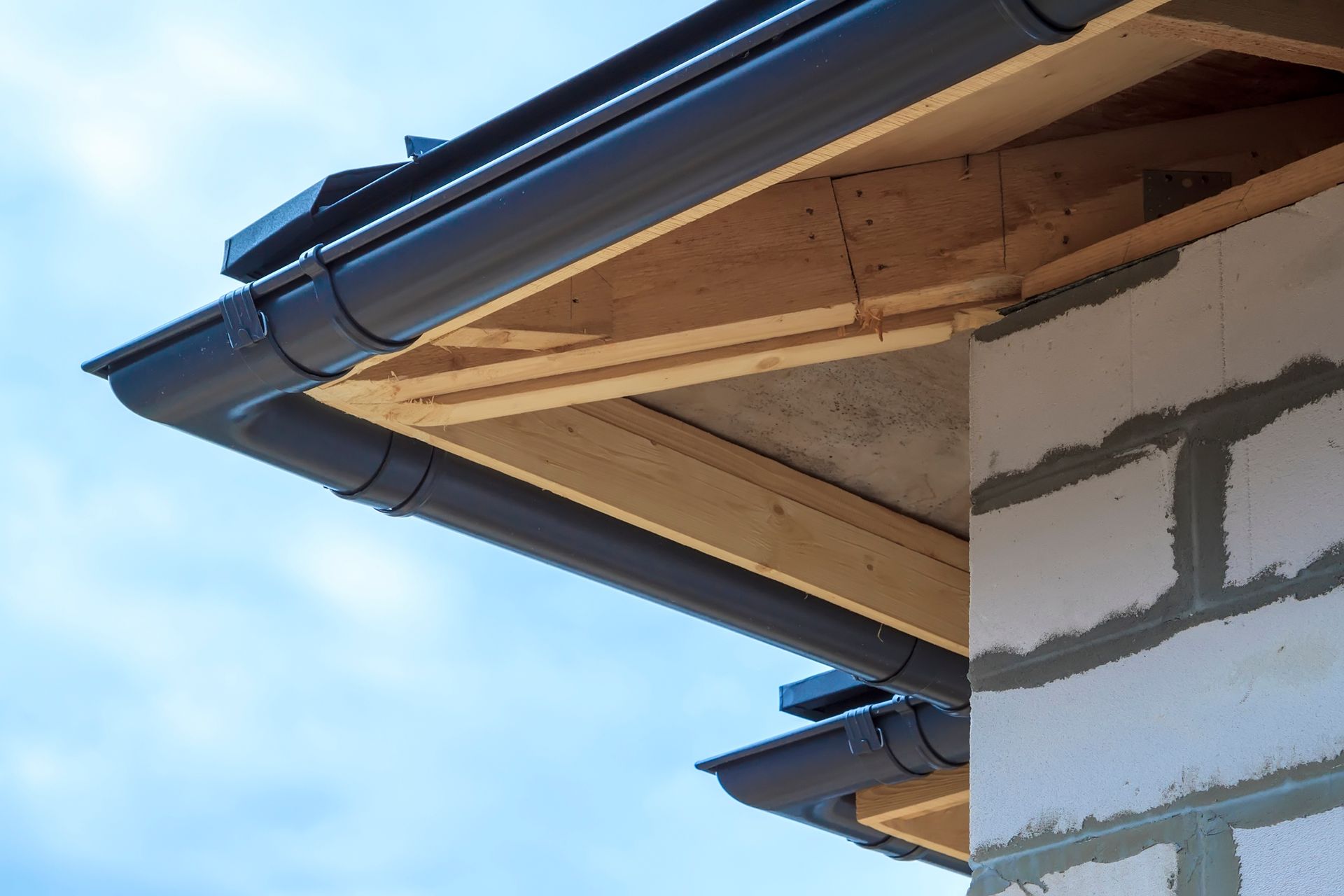 A close up of a gutter on the side of a building under construction.