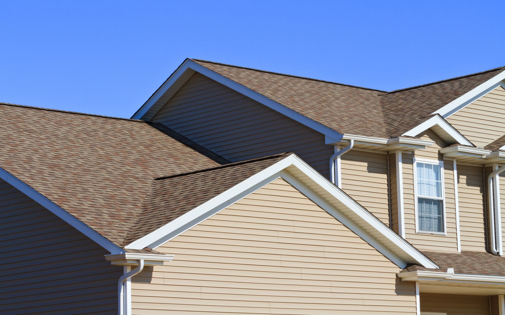 A house with a brown roof and a blue sky in the background