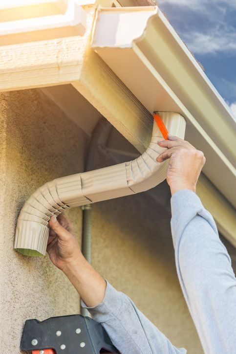 A man is measuring a gutter with a tape measure.