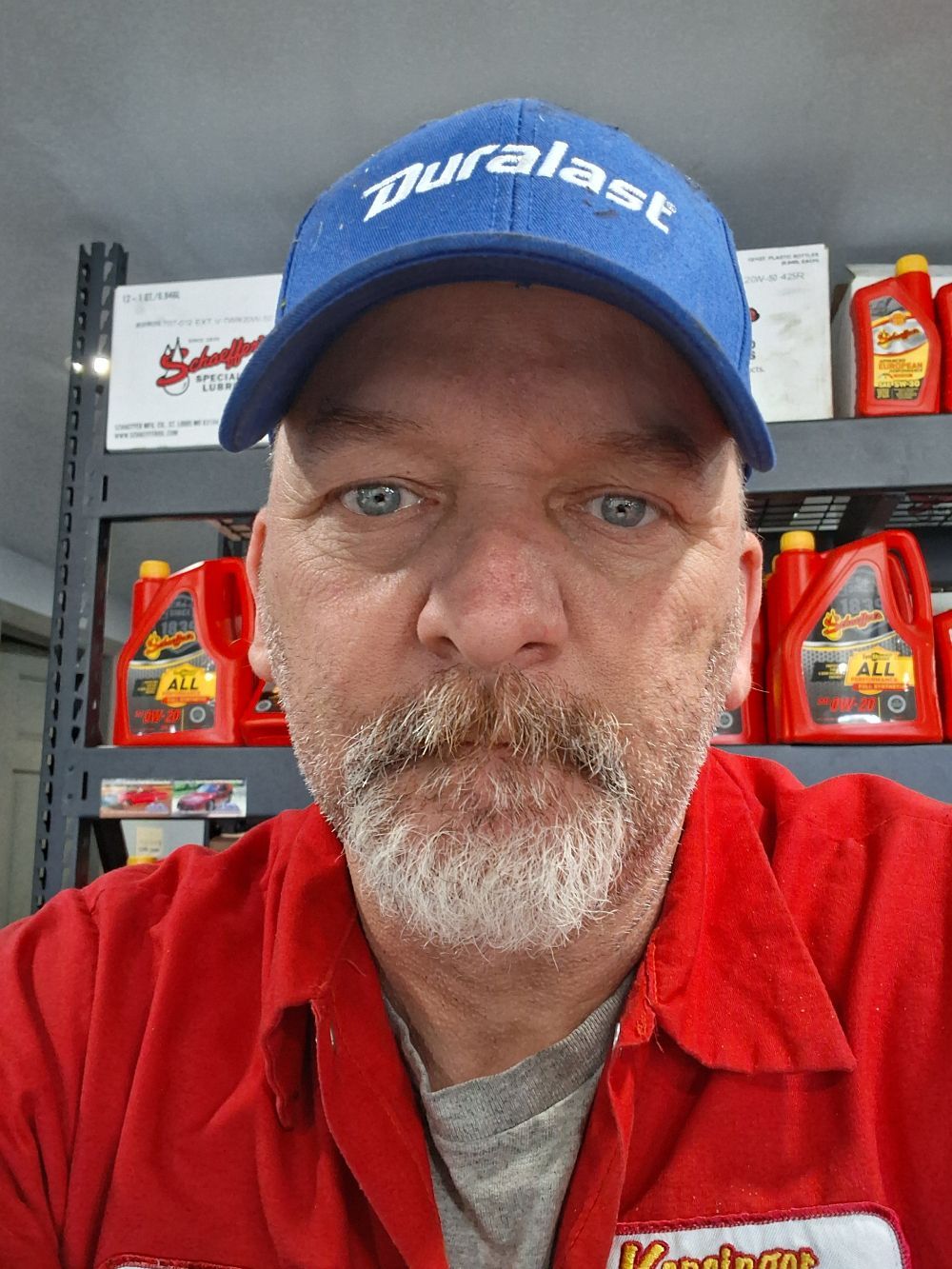 Man in blue Duralast cap and red shirt standing in an auto parts store aisle | Kensinger Repair Center