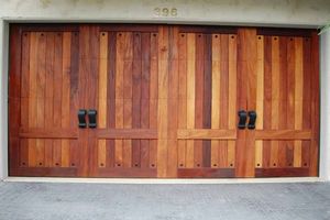 Wooden double garage door with black handles on a concrete driveway