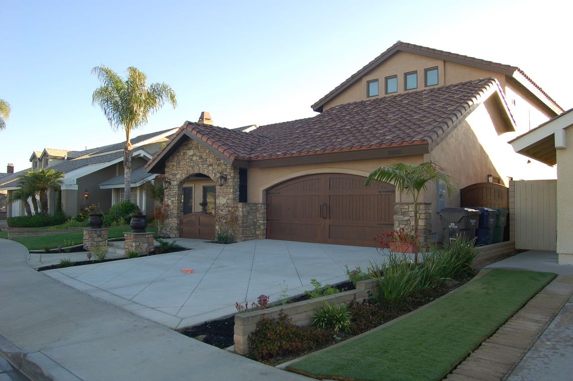 Suburban house with a brick facade, two-car garage, and a landscaped front yard at dusk