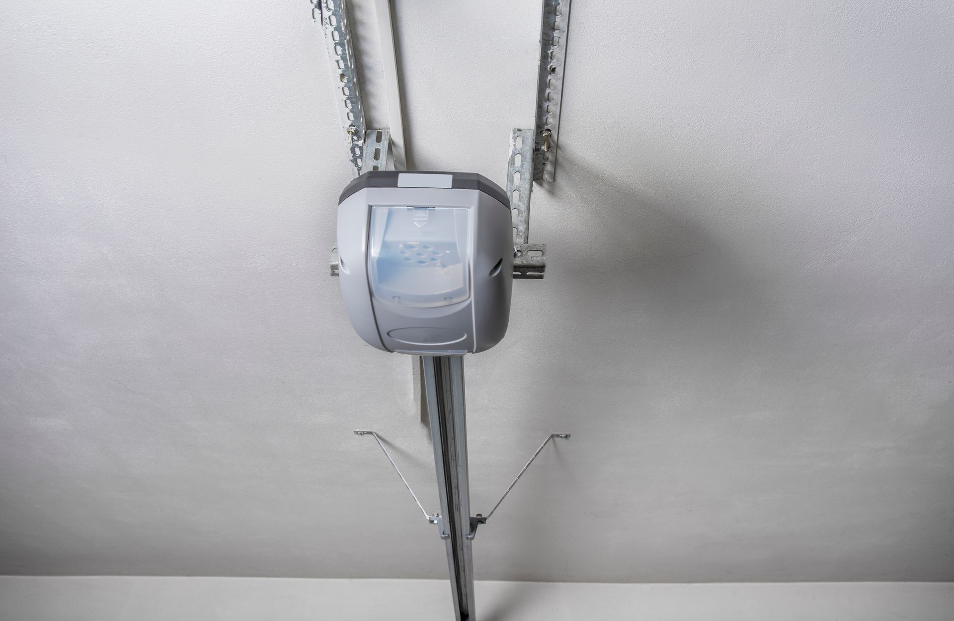 Ceiling-mounted garage door opener centered on a white ceiling with metal tracks