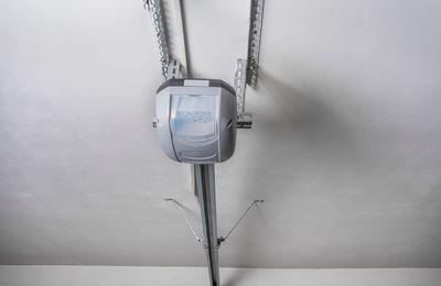 Ceiling-mounted garage door opener centered on a white ceiling with metal tracks