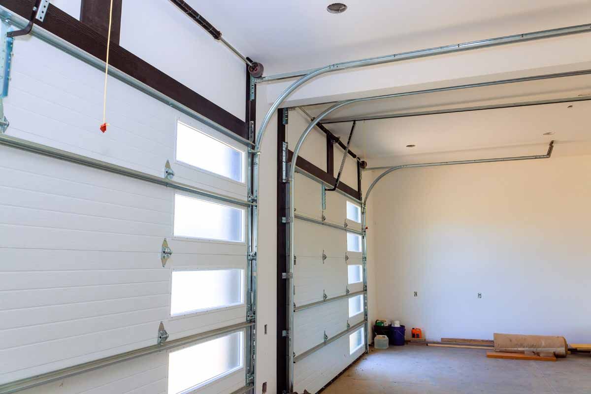 Empty garage interior with two white sectional doors and bare concrete floor