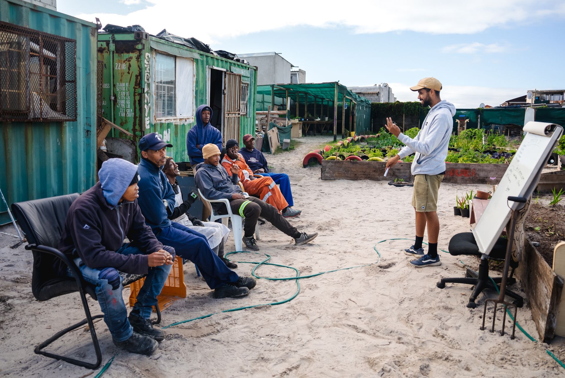 A man is standing in front of a group of people sitting on chairs.