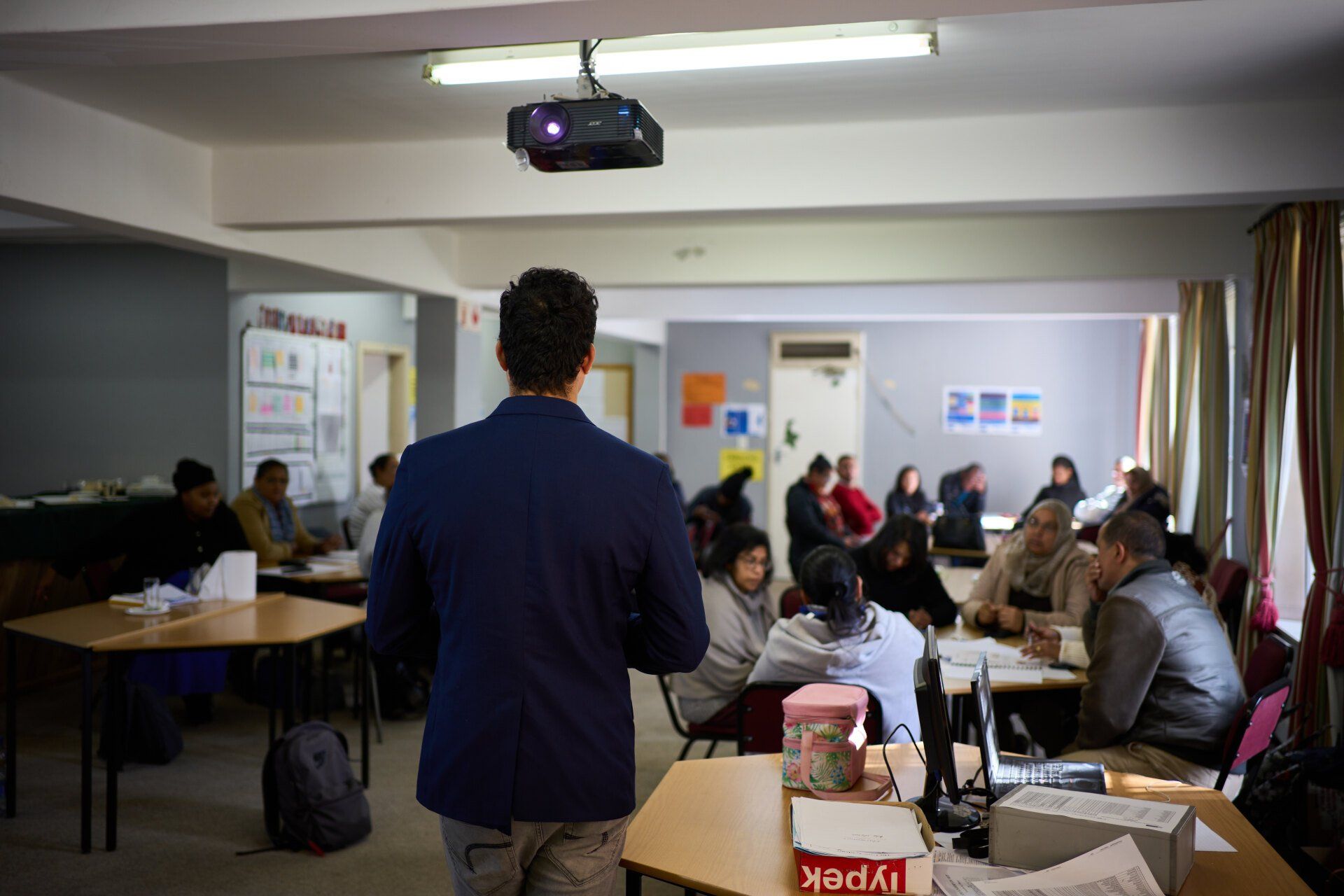 A man is standing in front of a group of people in a classroom.