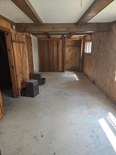 An empty room with wooden walls and a concrete floor.