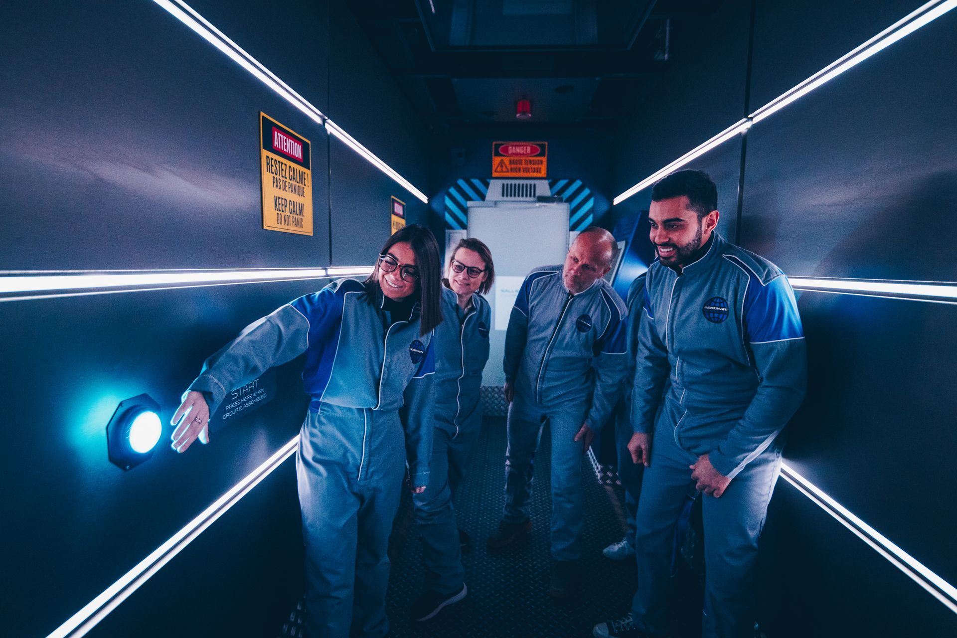 Un groupe de personnes en combinaison spatiale se tiennent dans une pièce sombre.