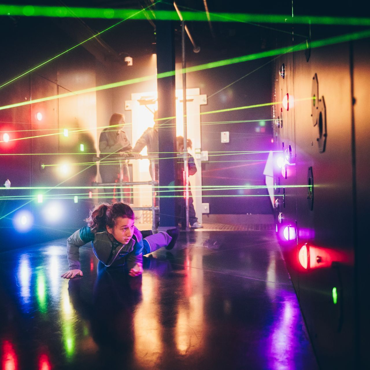 Un garçon rampe sur le sol dans une pièce avec des lasers sortant des murs.