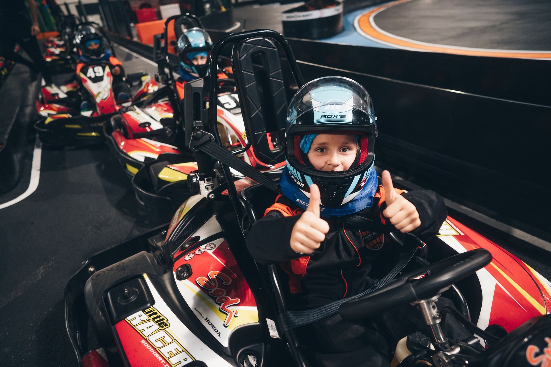 Un jeune garçon lève le pouce tout en étant assis dans un kart.