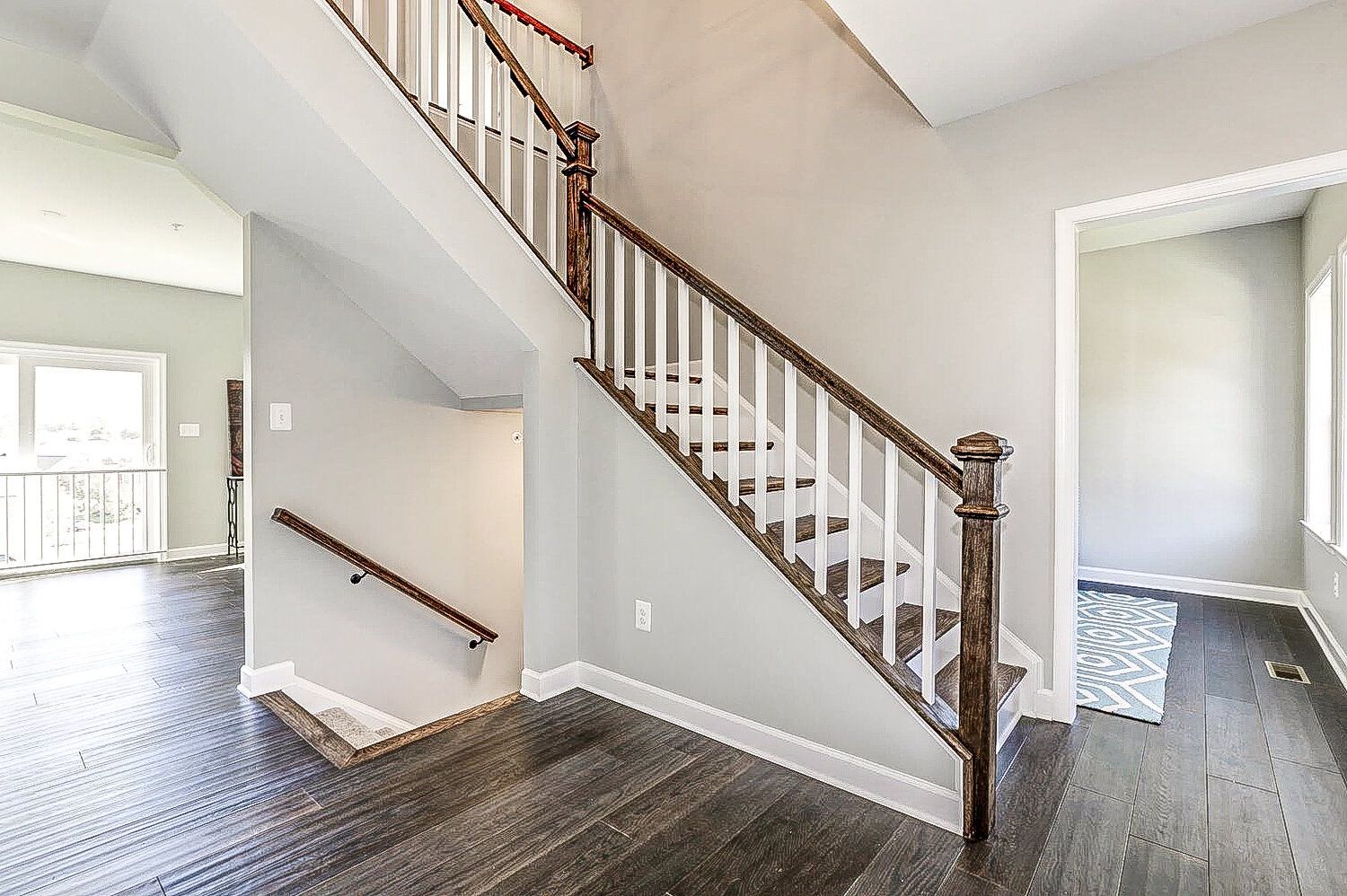 A staircase in a house with a wooden railing and a wooden floor.