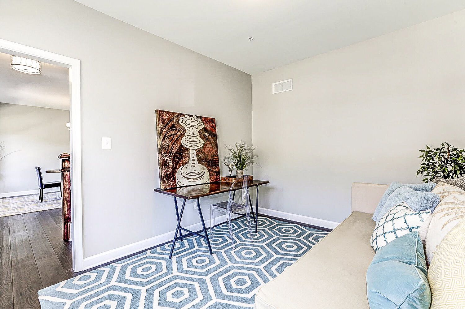 A living room with a couch , rug , table and painting on the wall.